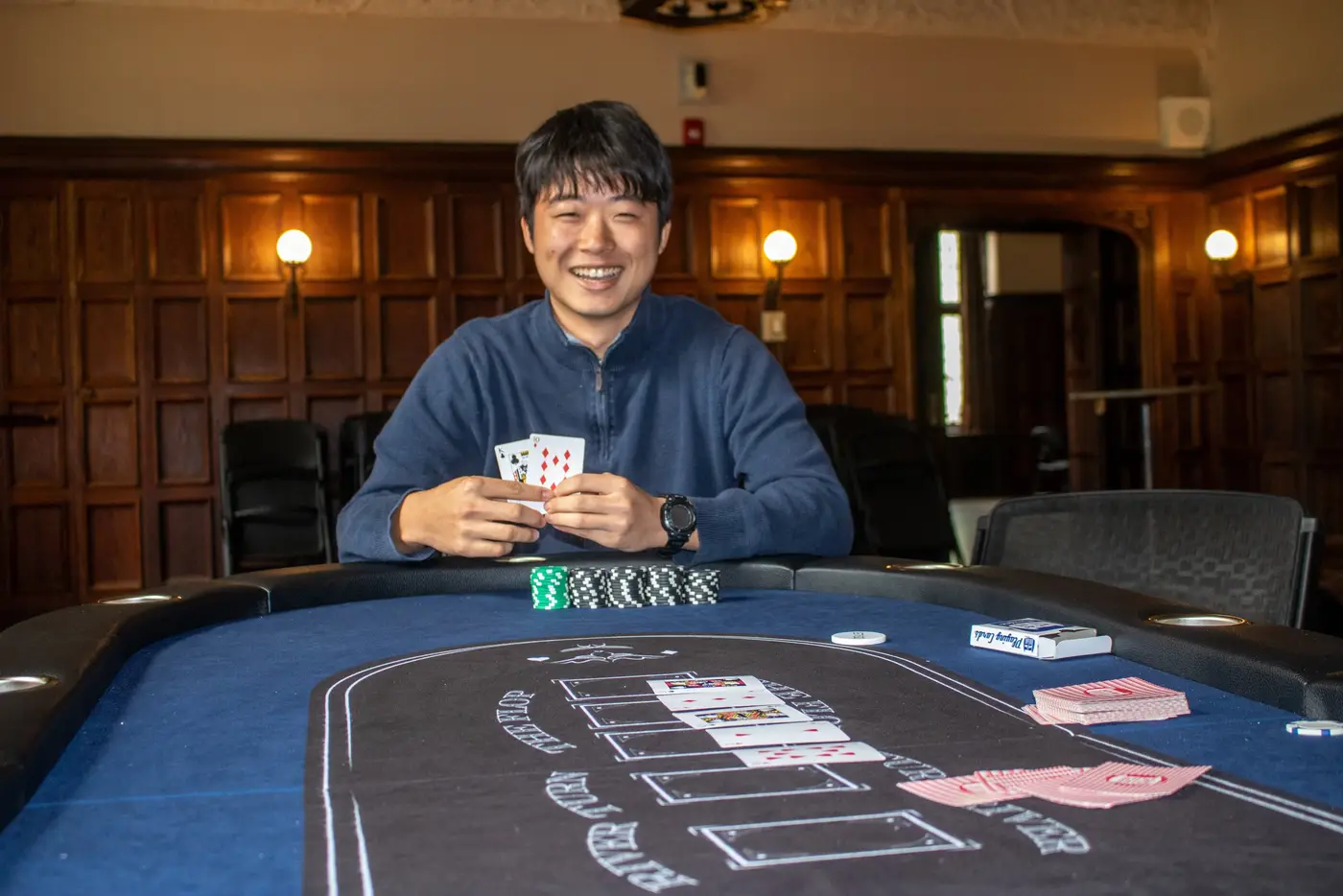 A member smiles while holding his cards at the table