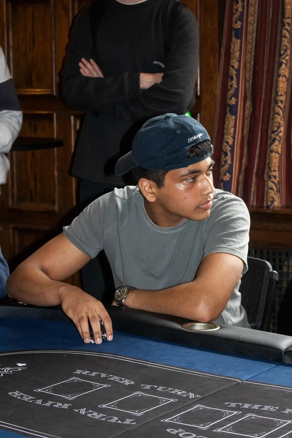 A player in a navy cap follows the action from his seat